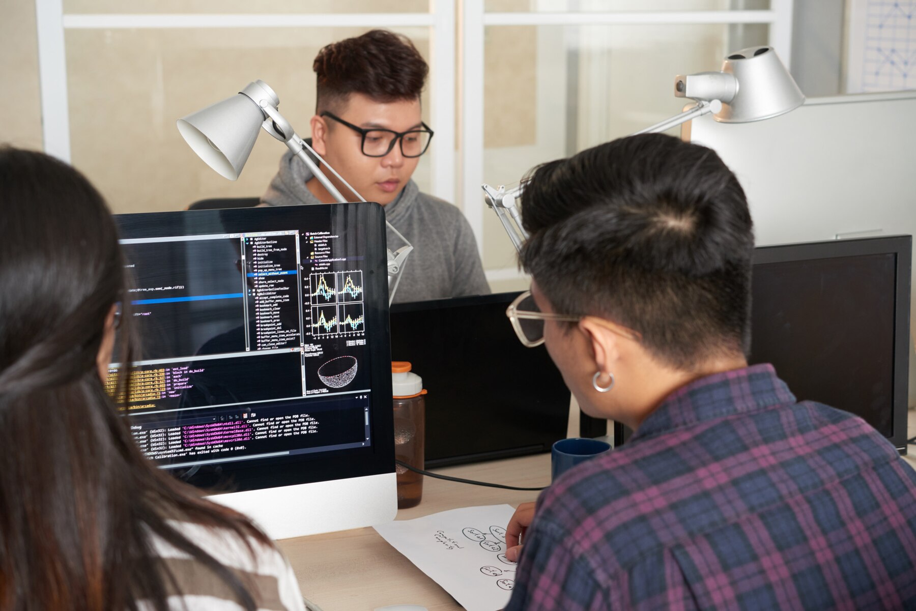 Engineers reviewing application code across desktop monitors